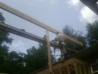Carpenter setting a ridge beam over a new addition frame — Ice Dam Removal by Roofing Brothers in Gillett