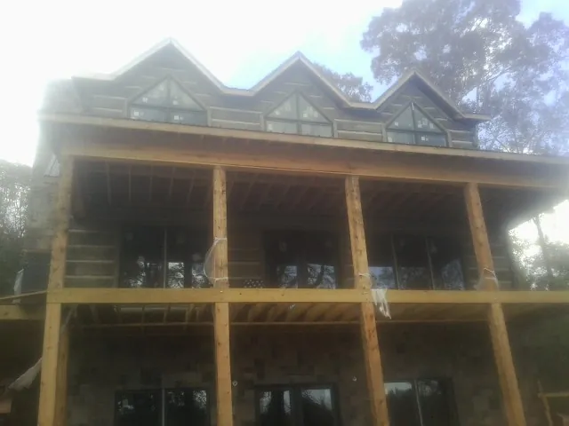 Dormers and porch framing on a large log home under construction — Roof Coating work by our crew in Gillett