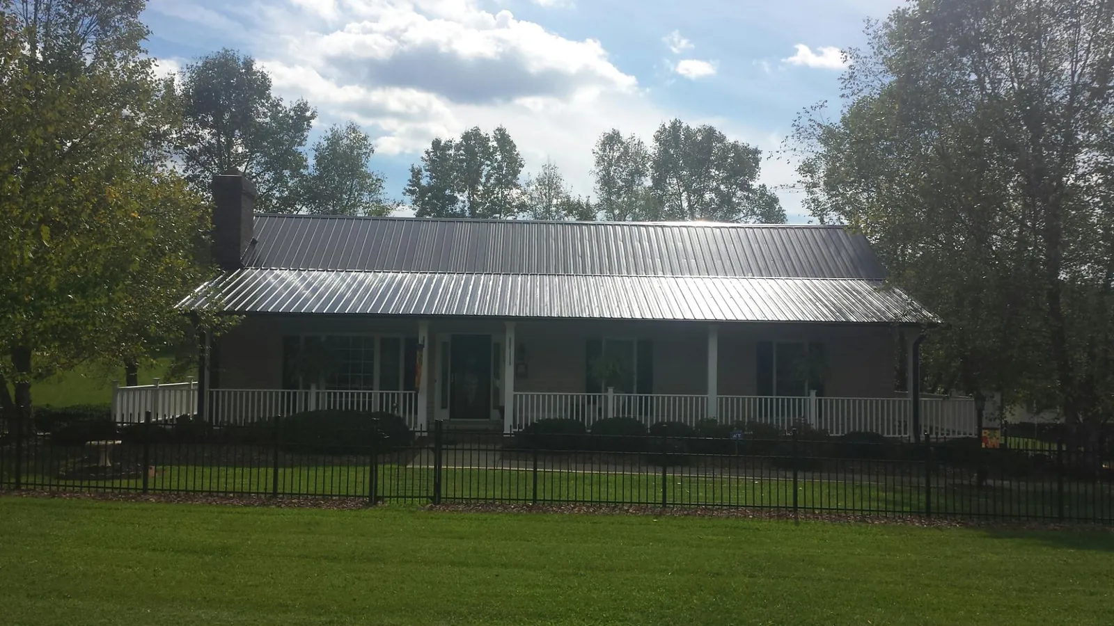 Gray metal roof on a brick ranch with a full width front porch — Gutter Guard Installation work by our crew in Gillett
