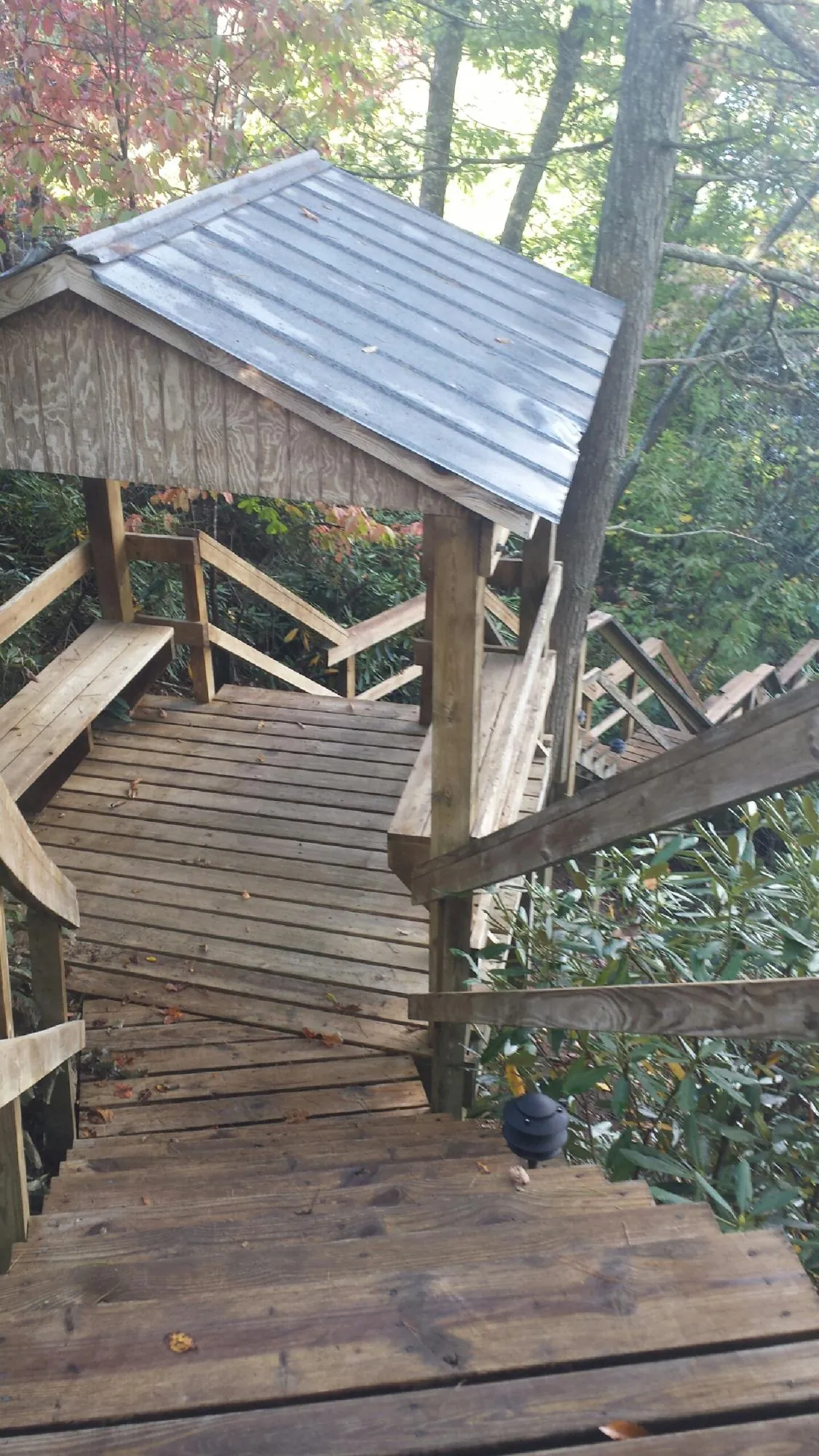Metal roofed shelter over wooden steps on a wooded walkway — Skylight Repair & Installation work by our crew in Gillett