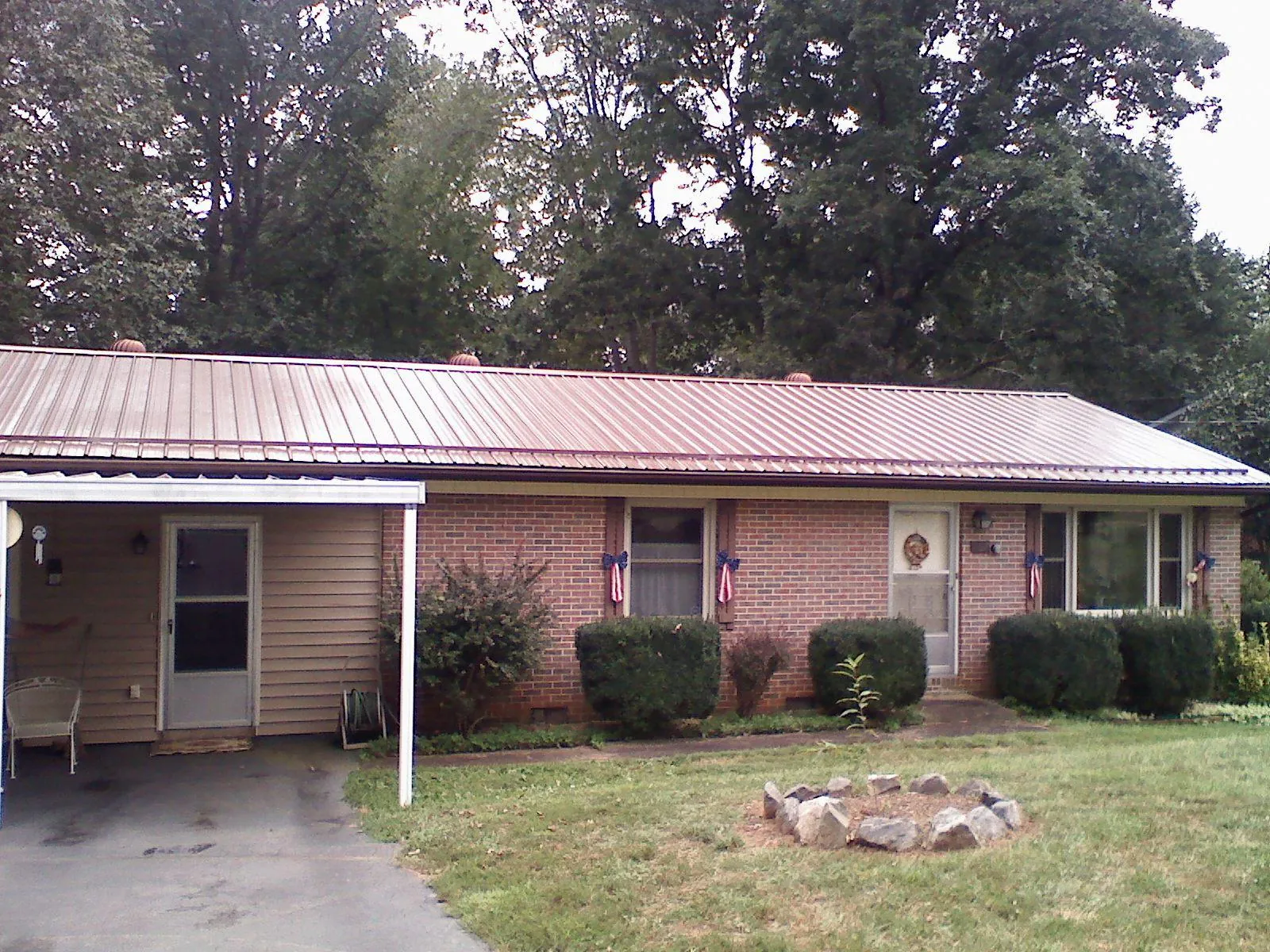 Bronze metal roof and carport on a brick ranch home — Roof Repair work by our crew in Gillett