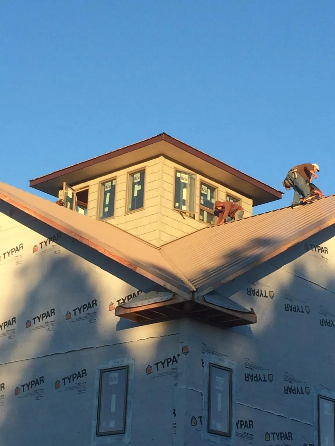 Roofers working around a rooftop cupola on a new metal roof at sunset — Roof Waterproofing in Gillett by Roofing Brothers